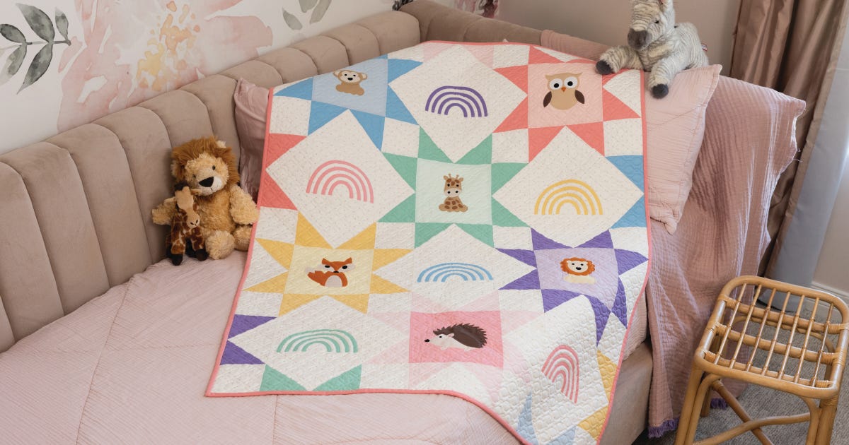 Zoo Crew baby quilt featuring pastel star blocks and appliqué zoo animals, draped over a nursery chair in a soft, modern nursery setting.