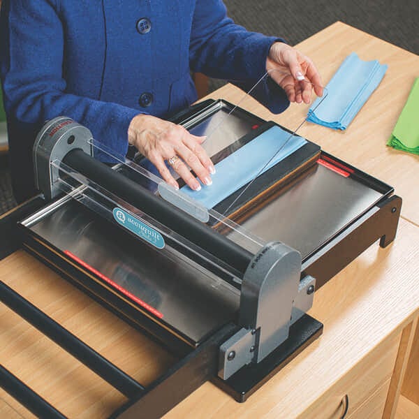 image of hands placing pieces of cloth and cutting mat onto die board