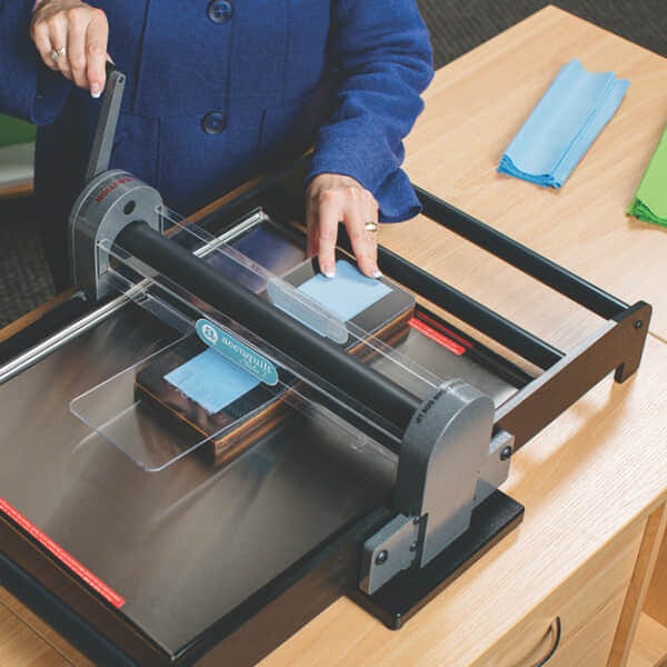 image of hands rolling the die, fabric and cutting mat through Studio 2 Cutter