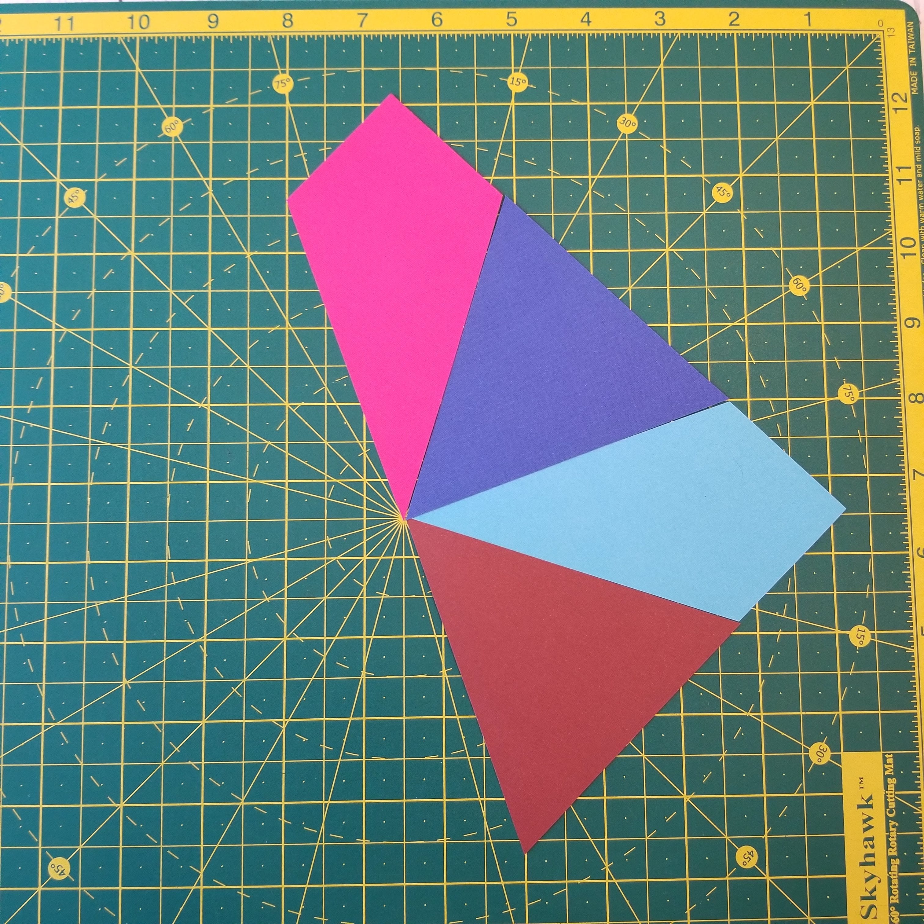 Half a quilt block made up of kite shapes and triangles on self healing cutting mat