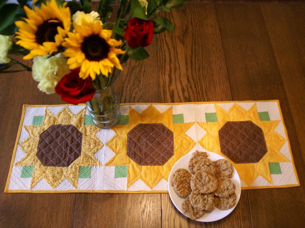 quilted sunflower table runner with a fall bouquet in a vase and oatmeal sunflower seed cookies