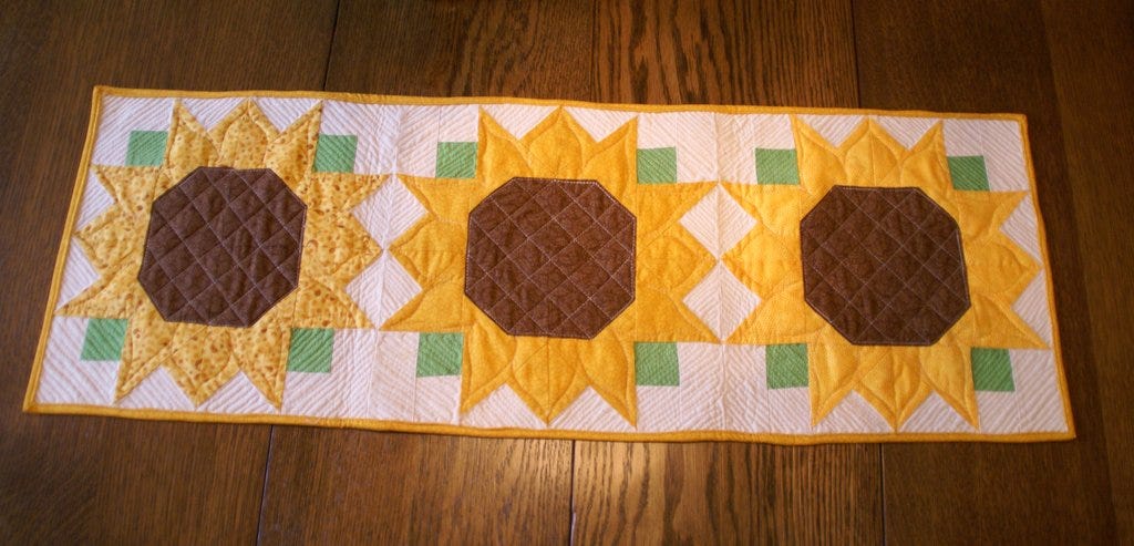 completed sunflower quilted table runner on wooden table