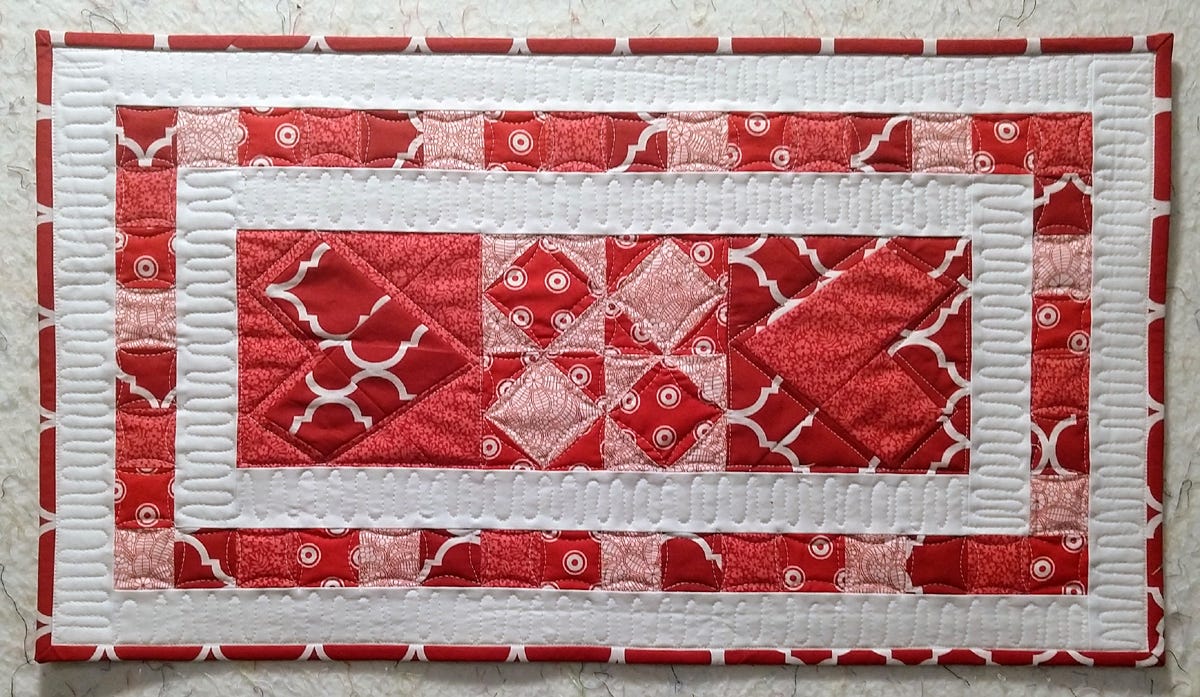 quilted red, white and pink heart table runner made with accuquilt wonky heart block