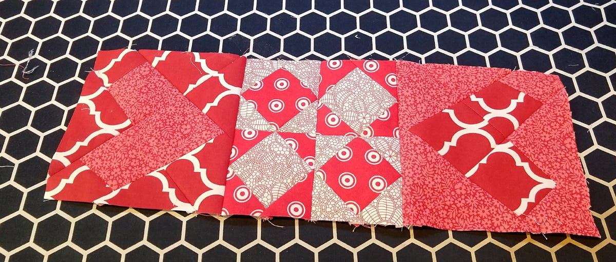 three red and white quilt blocks sewn together with wonky hearts on either side of a four patch of on point square blocks