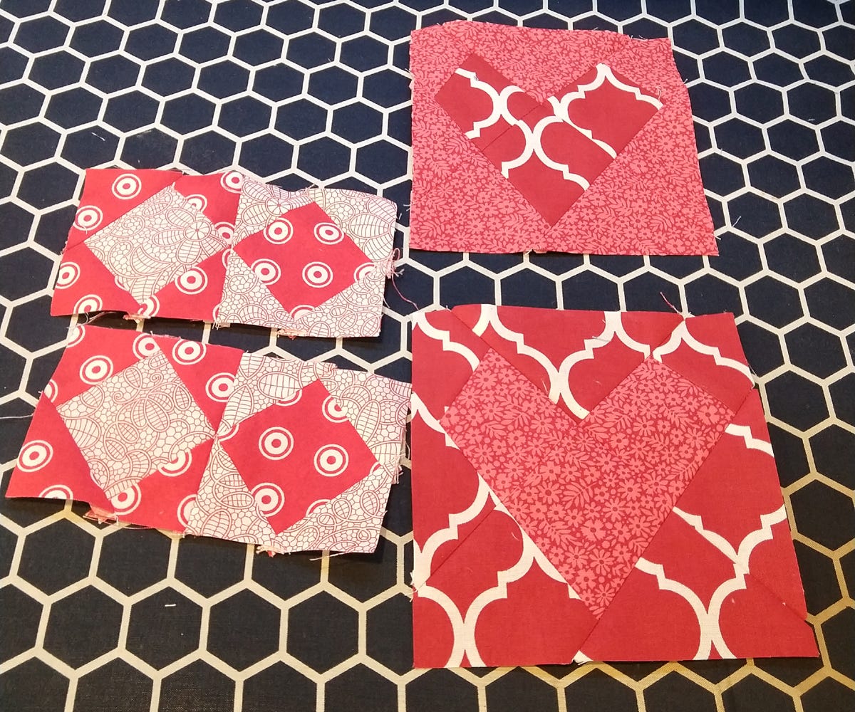 completed wonky heart quilt blocks with on point square and triangle blocks sewn in pairs on a black and white honeycomb sewing surface