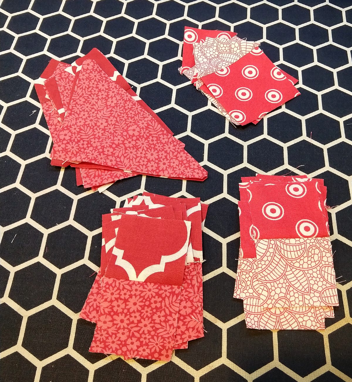 red and white fabric squares sewn to squares and on point squares with half square triangles on black and white honeycomb surface